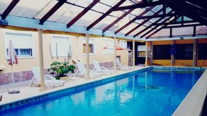 Piscina interna con lettini e zona coperta.