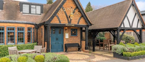 A traditional building with a 'Welcome' sign, a wooden bench, and outdoor seating.