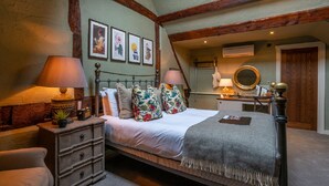 A traditional bedroom with a four-poster bed, a dresser, a mirror, and a small desk with a lamp.
