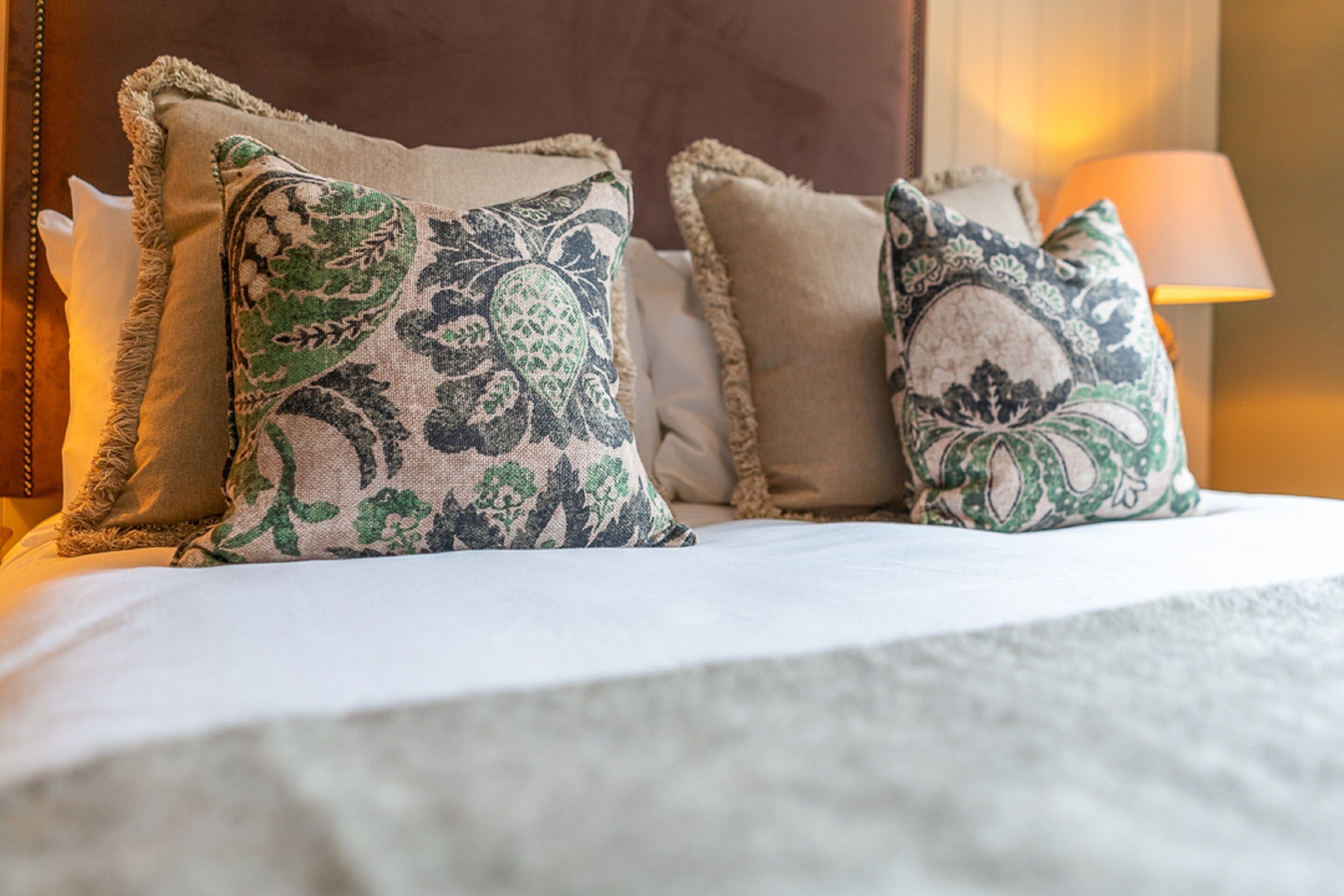 A bed with two decorative pillows and a bedside lamp.
