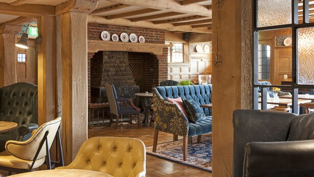 A cozy interior with a brick fireplace, wooden beams, and comfortable seating areas.