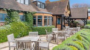 A traditional building with a corner turret, wooden outdoor seating, and a well-maintained garden.