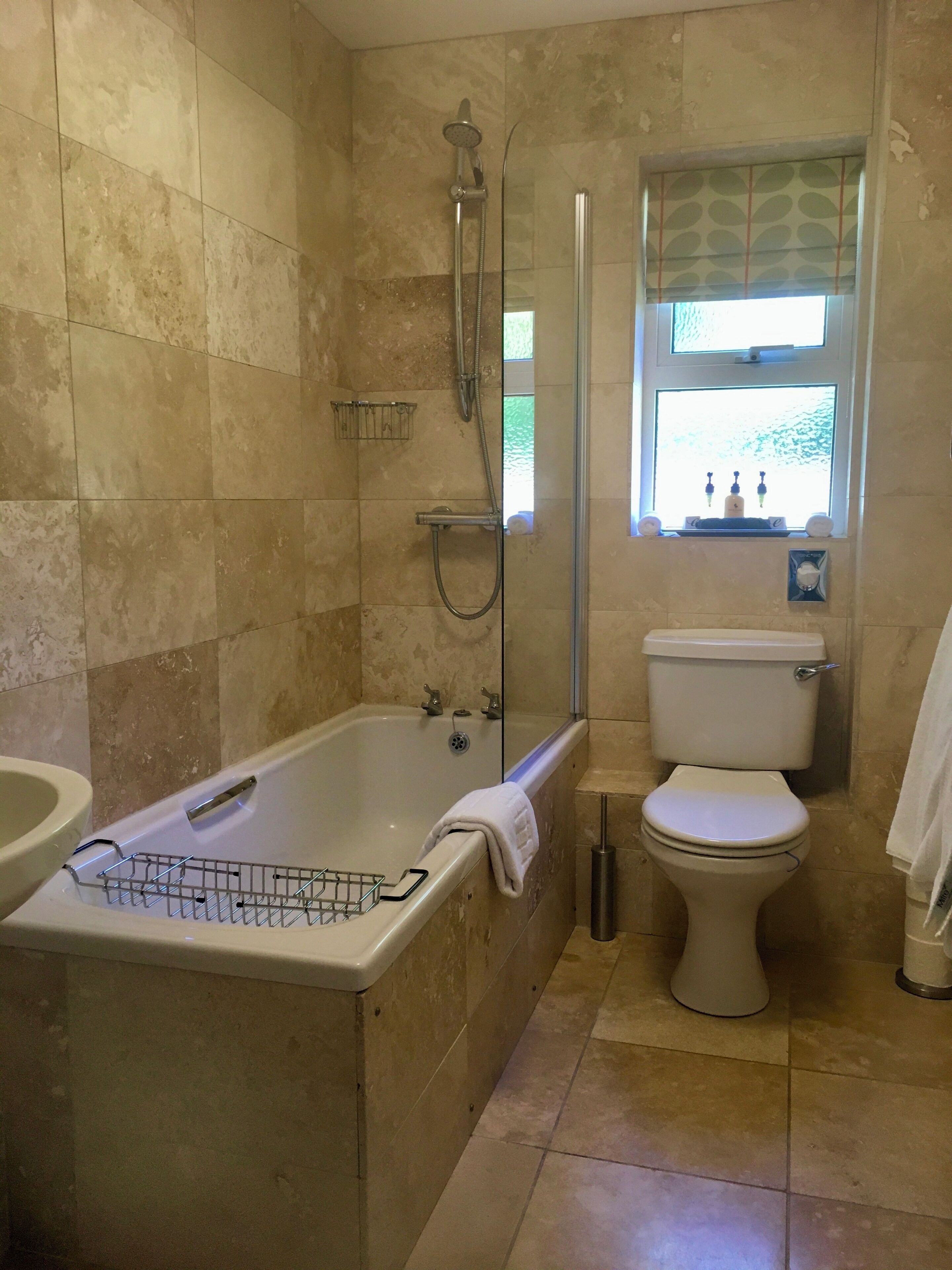 A bathroom with a bathtub, toilet, and a window with a view of greenery.