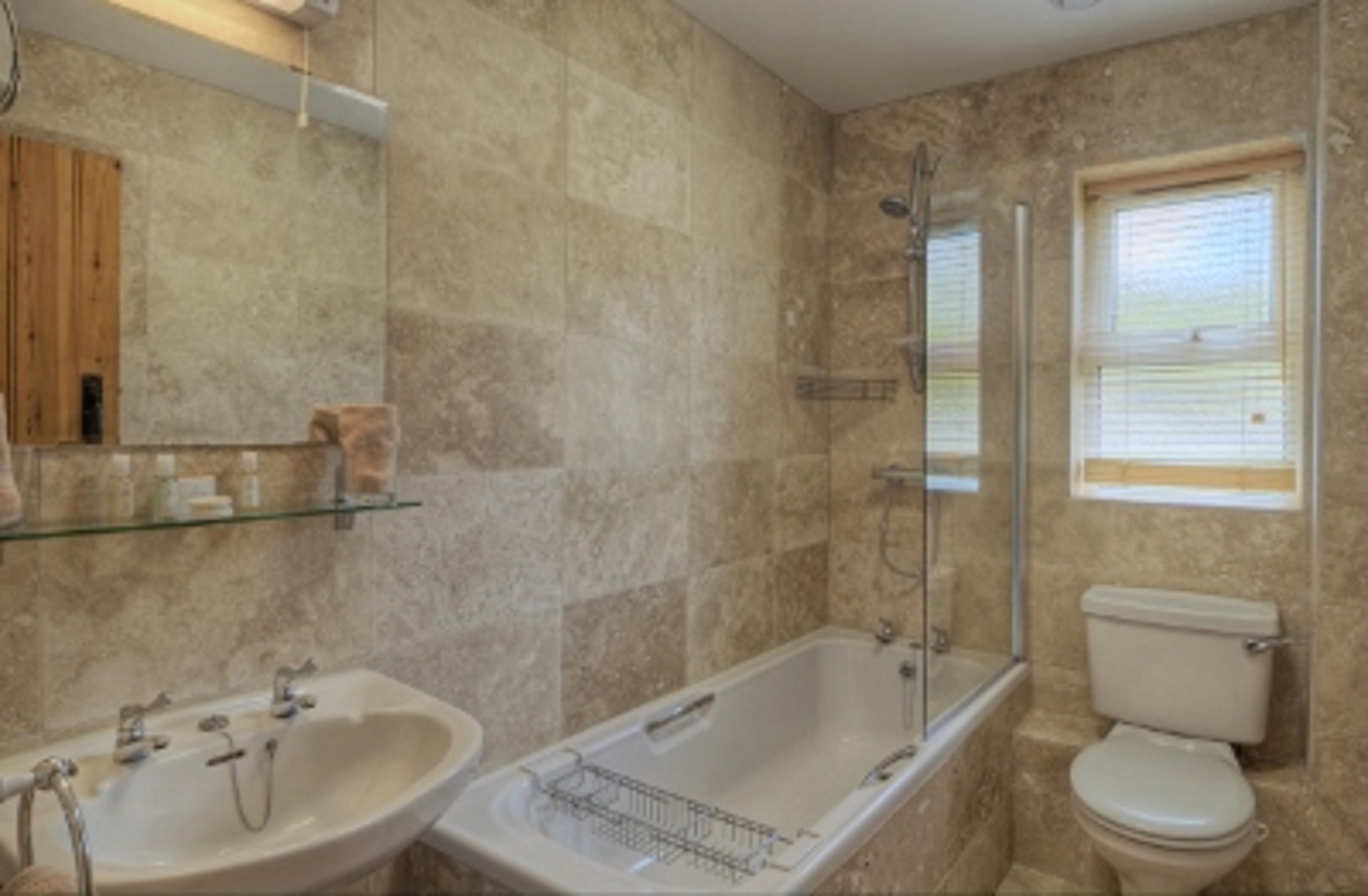 A bathroom with a bathtub, sink, and toilet, all in a neutral color scheme.
