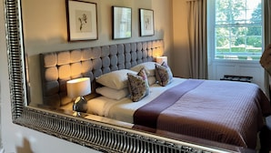 A neatly arranged bedroom with a large bed, framed artwork on the wall, and a window with curtains. - Chatton Park House Hotel Adult Only (Alnwick)