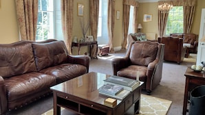 A spacious living room with leather sofas, a wooden coffee table, and a chandelier. - Chatton Park House Hotel Adult Only (Alnwick)