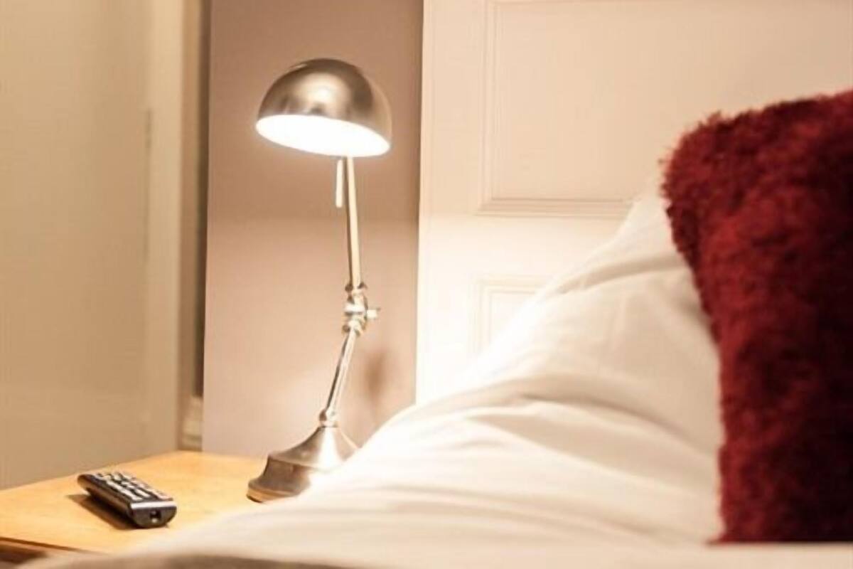 Une chambre d’hôtel avec un lit, une table de chevet, une lampe et une télécommande.