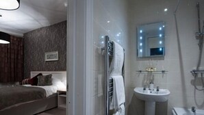 A modern hotel room with a large bed, a bathroom with a sink, mirror, and shower.