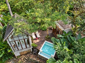 Un complexe hôtelier tropical doté d’une piscine, d’une terrasse en bois et d’une végétation luxuriante.