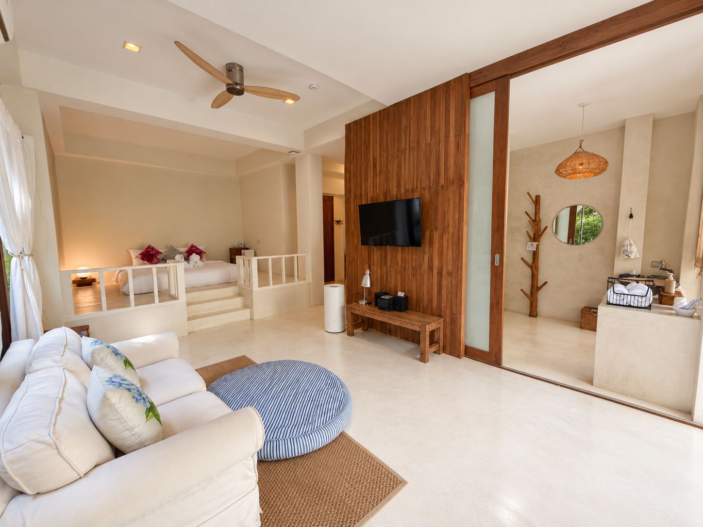 A modern living room with a sofa, a television, and a wooden wall.
