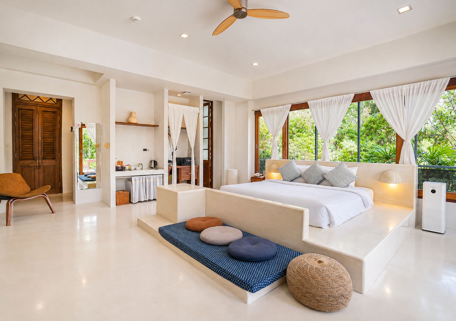Un dormitorio moderno con una cama grande, un espacio de descanso y vistas a zonas verdes.
