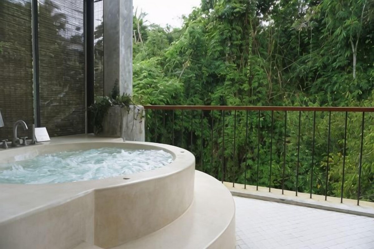 A hot tub on a balcony with a view of dense greenery.