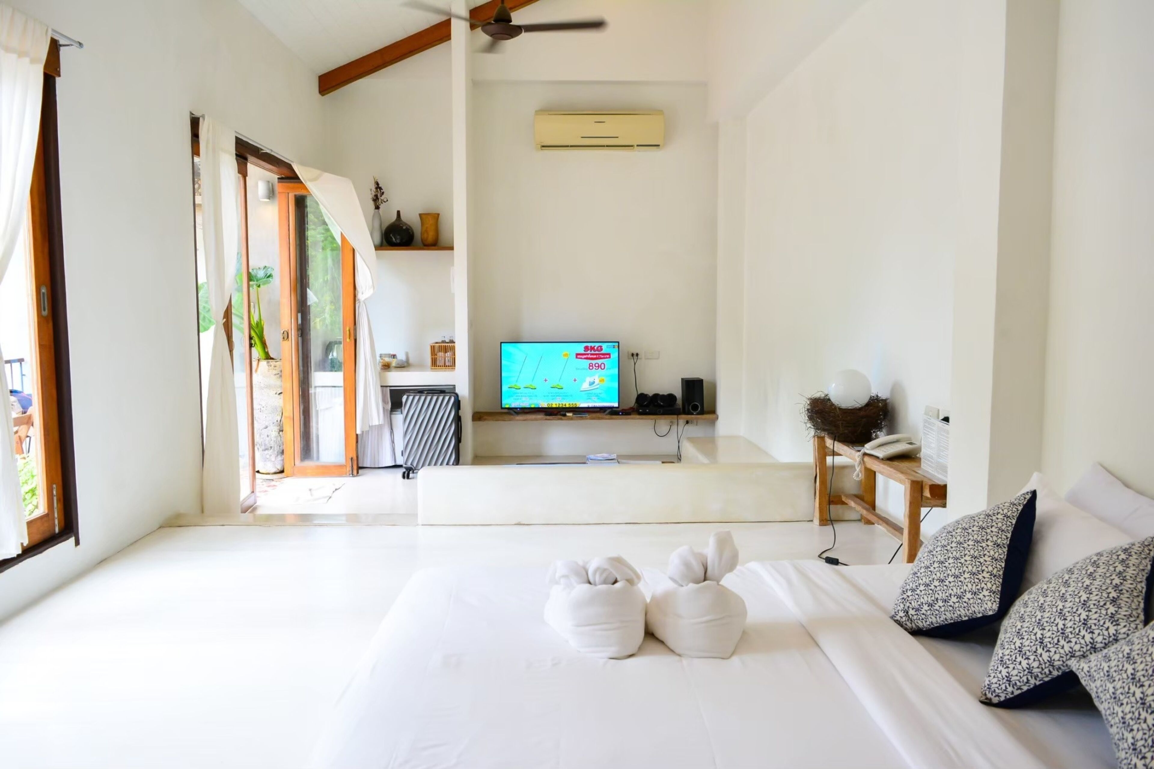 A hotel room with a bed, a TV, a desk, and a window.
