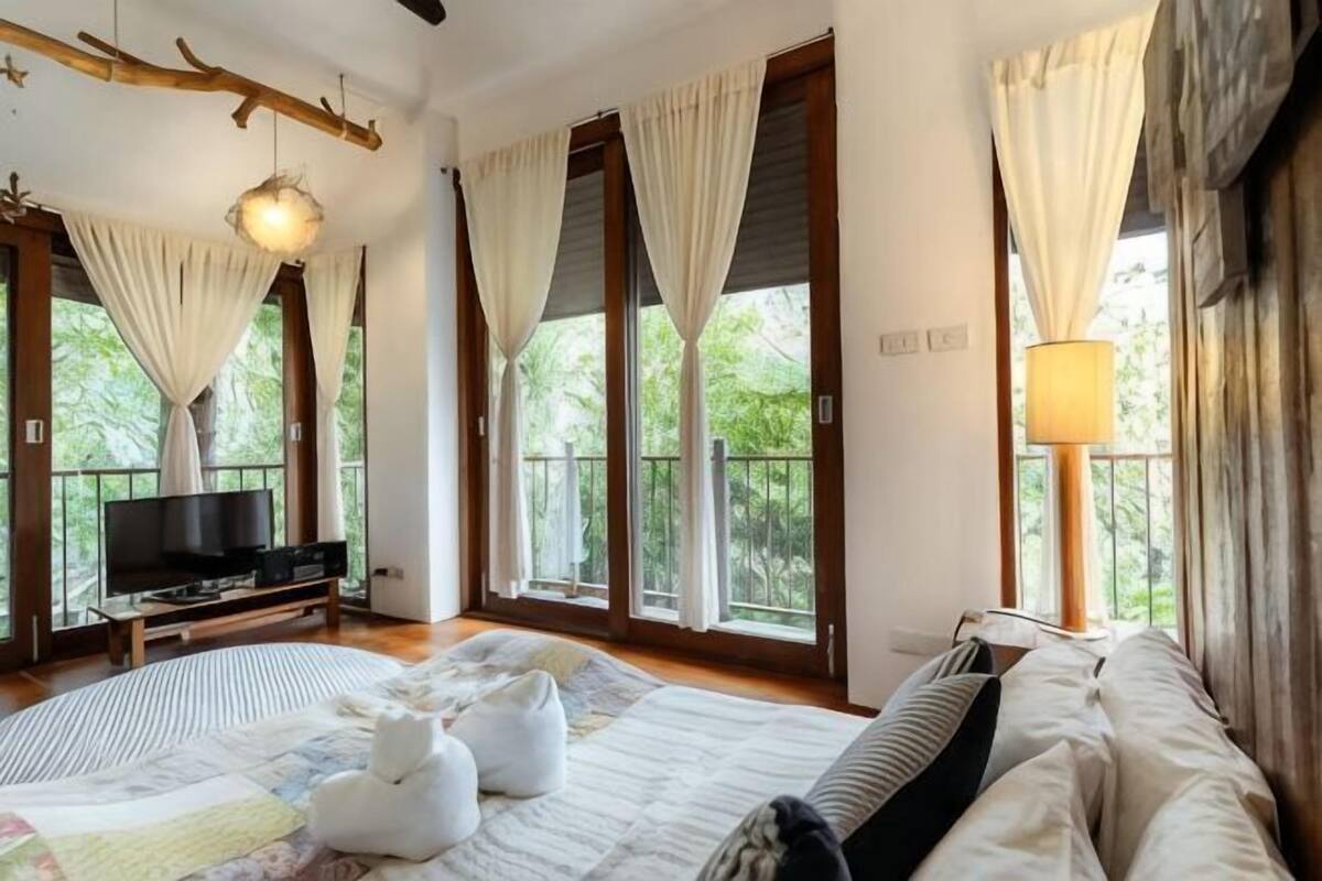 Un dormitorio con cama, televisión y balcón con cortinas.