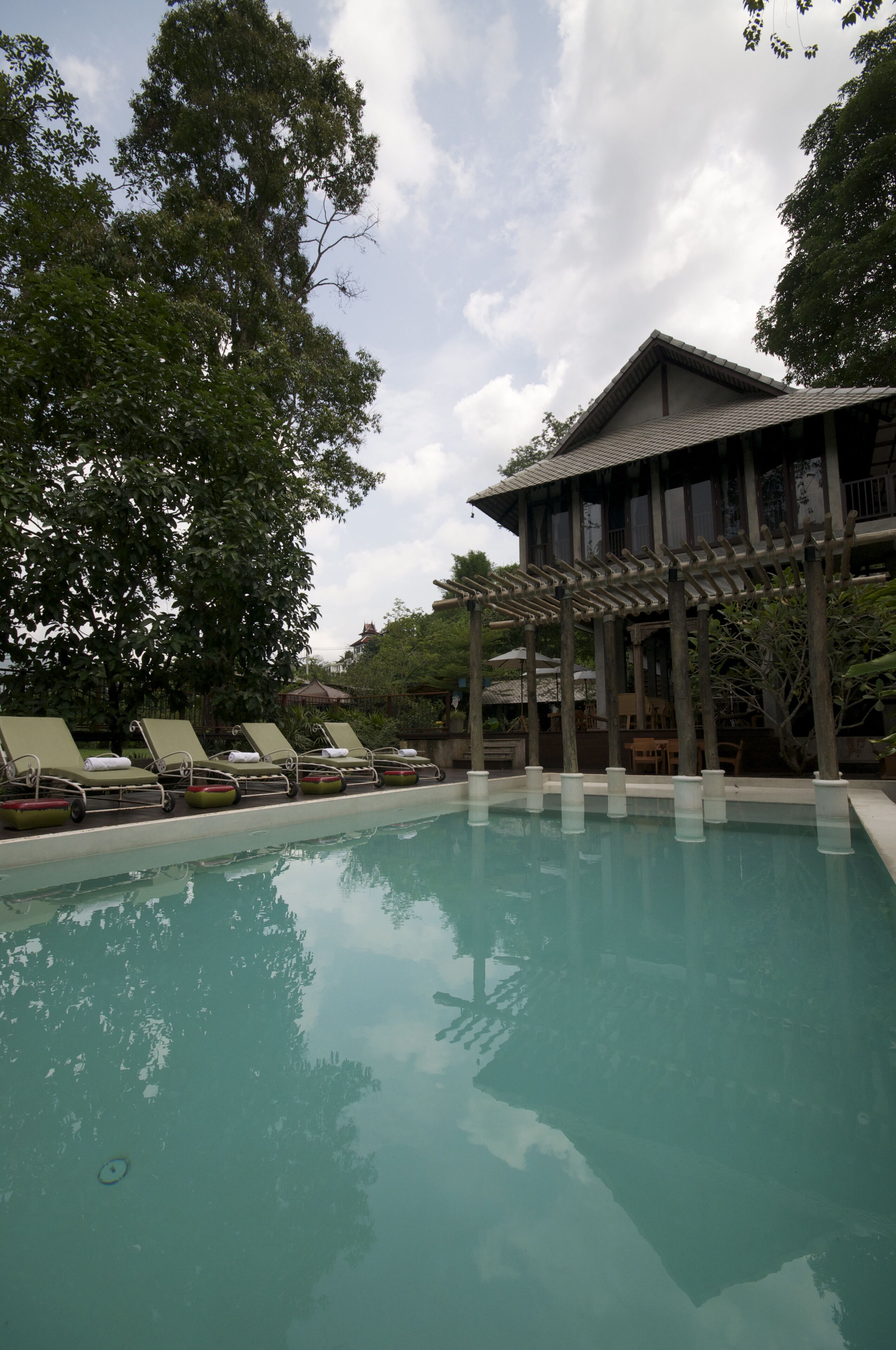 A pool area with lounge chairs and a building with a traditional architectural style.