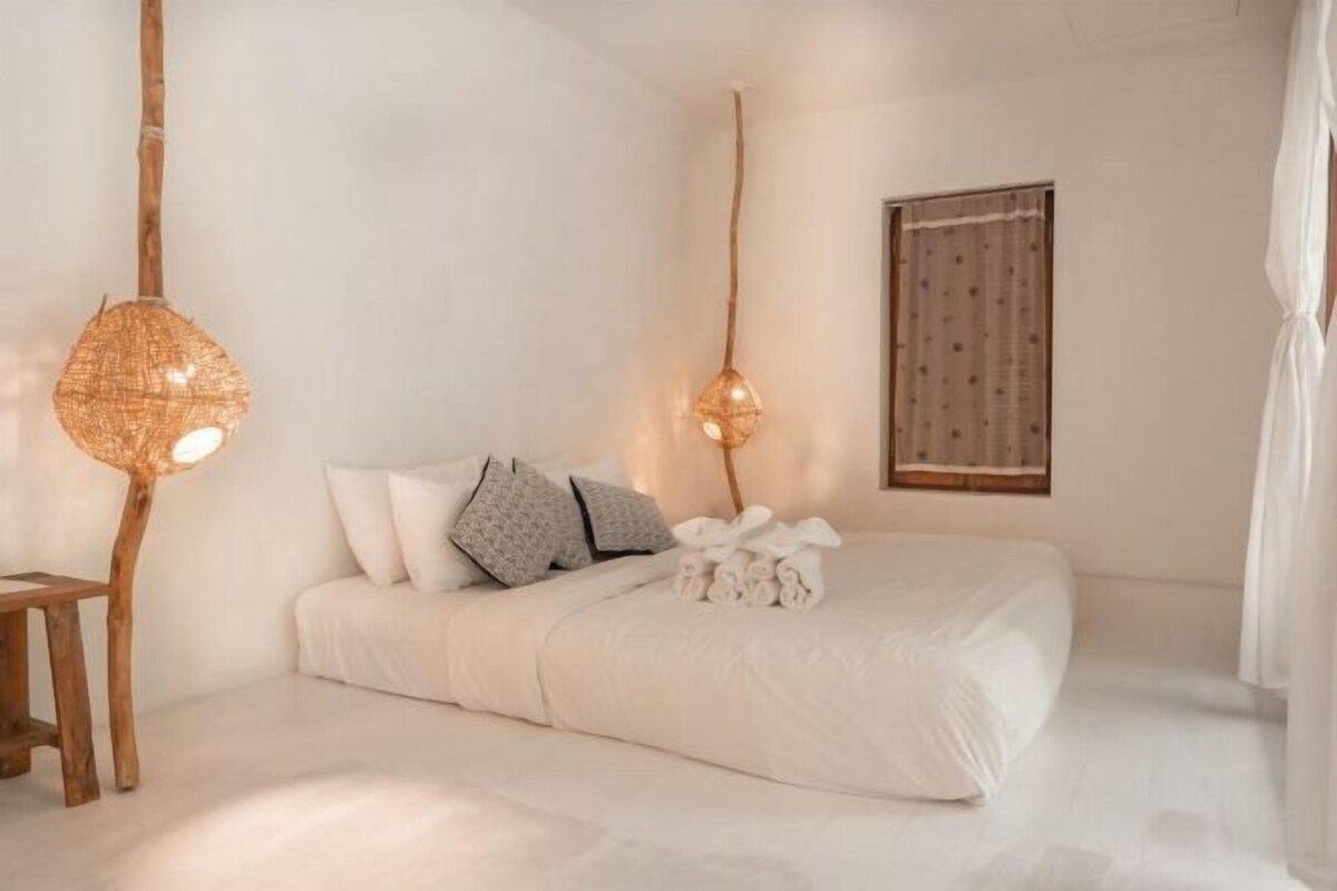 A minimalist bedroom with a bed, bedside table, and two wall-mounted lamps.