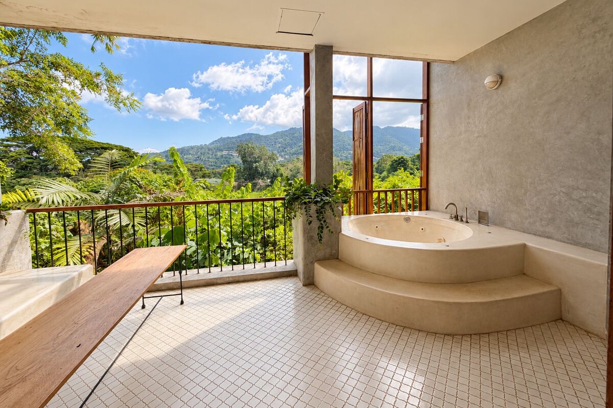 Un baño con una bañera grande, un banco de madera y vistas a un paisaje exuberante.