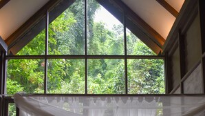 Un dormitorio con cama a dosel, vista a follaje exuberante y cabecera de madera.