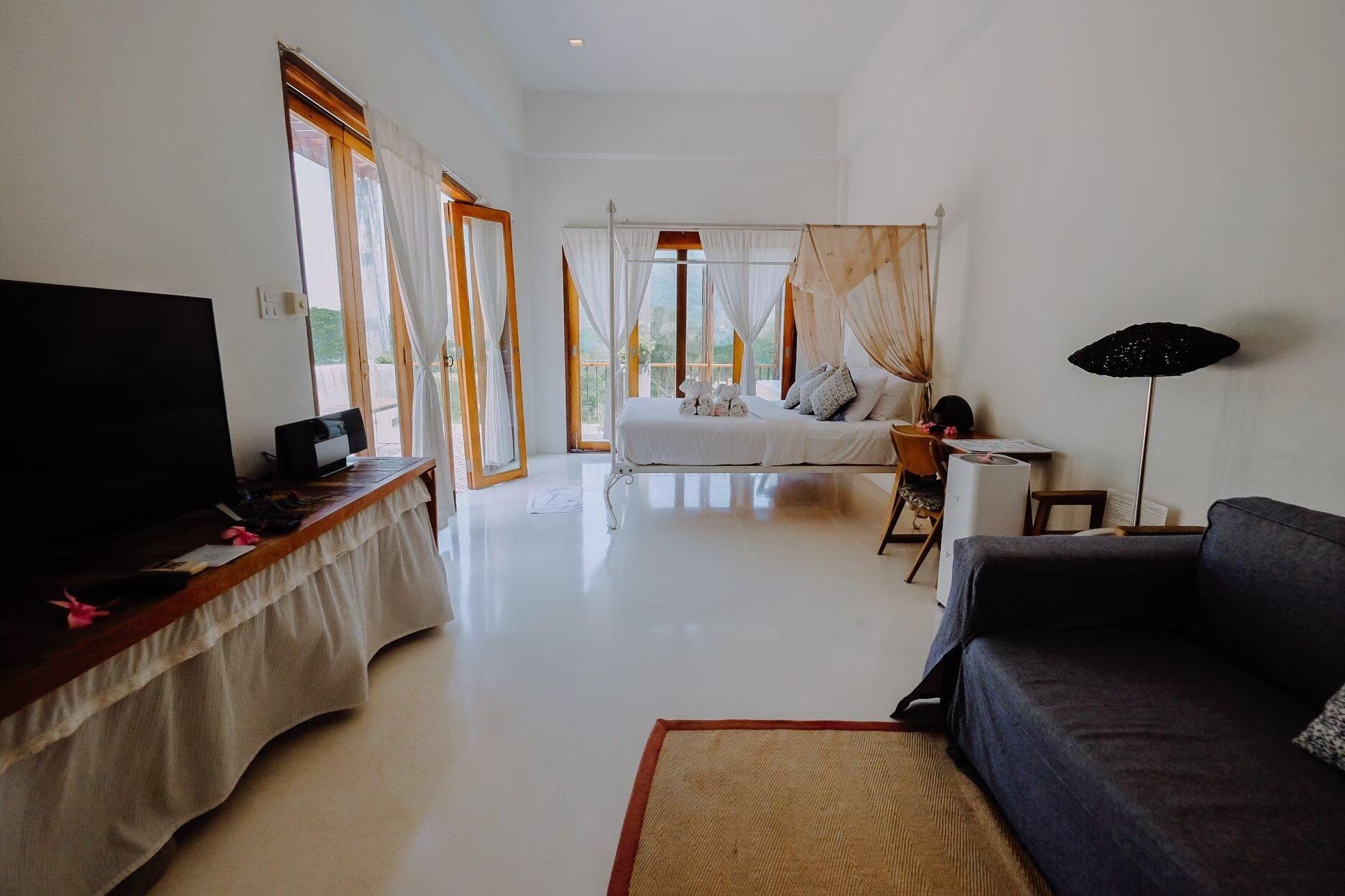 A spacious room with a bed, a desk, a TV, and a sofa.
