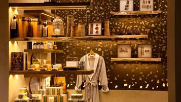A well-organized retail space with shelves displaying various products, a hanging robe, and decorative items against a patterned wall.