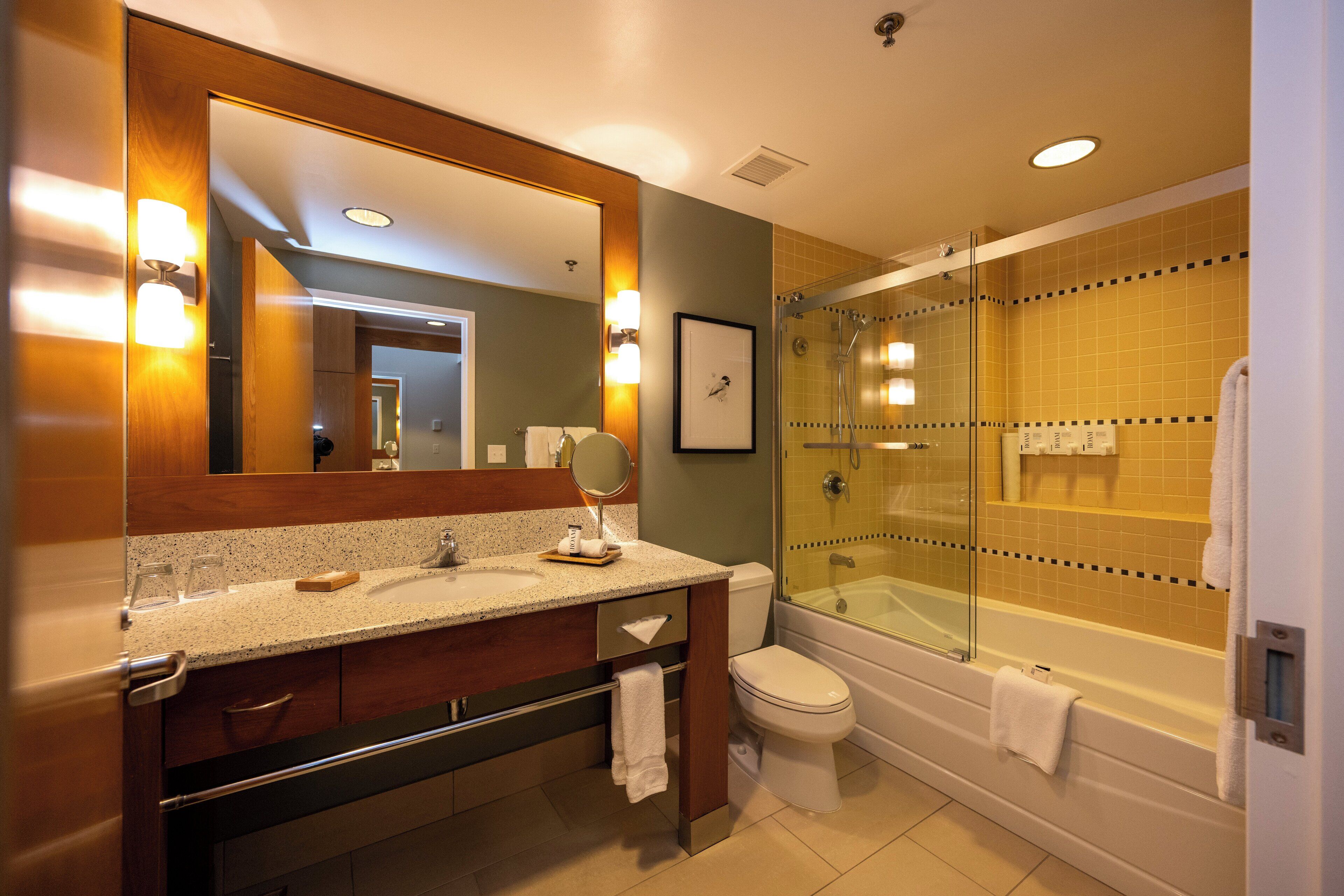 Un baño moderno con tocador doble, ducha con cerramiento de vidrio y retrete.