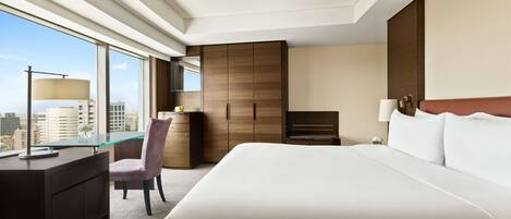 Une chambre d’hôtel avec un grand lit, un bureau avec une chaise, une armoire et une vue sur la ville.
