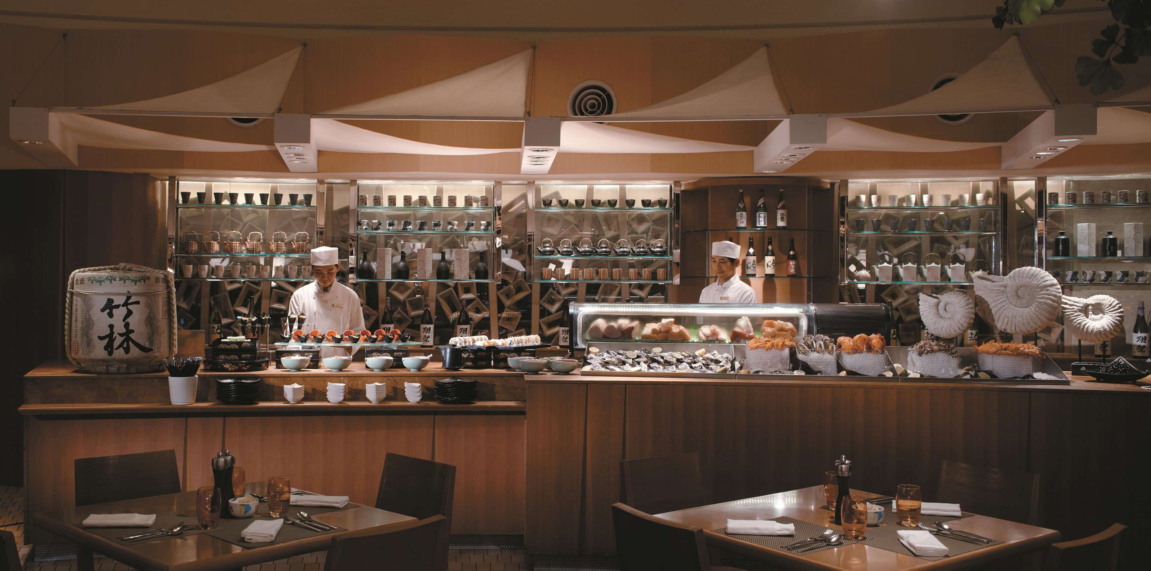 A restaurant interior with a sushi bar, wooden decor, and various food displays.
