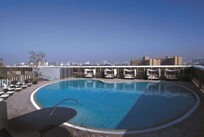 Una piscina en la azotea con sillones de descanso y vistas a la ciudad.