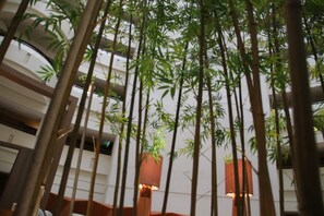 Un espacio interior de varios niveles con plantas de bambú e iluminación moderna.