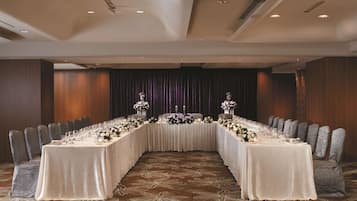 Un salón de conferencias con una larga mesa dispuesta para una reunión, rodeado de sillas.