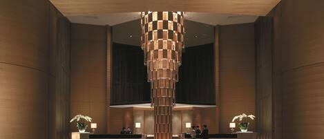 A modern reception area with a central pillar, reception desk, seating, and potted plants.