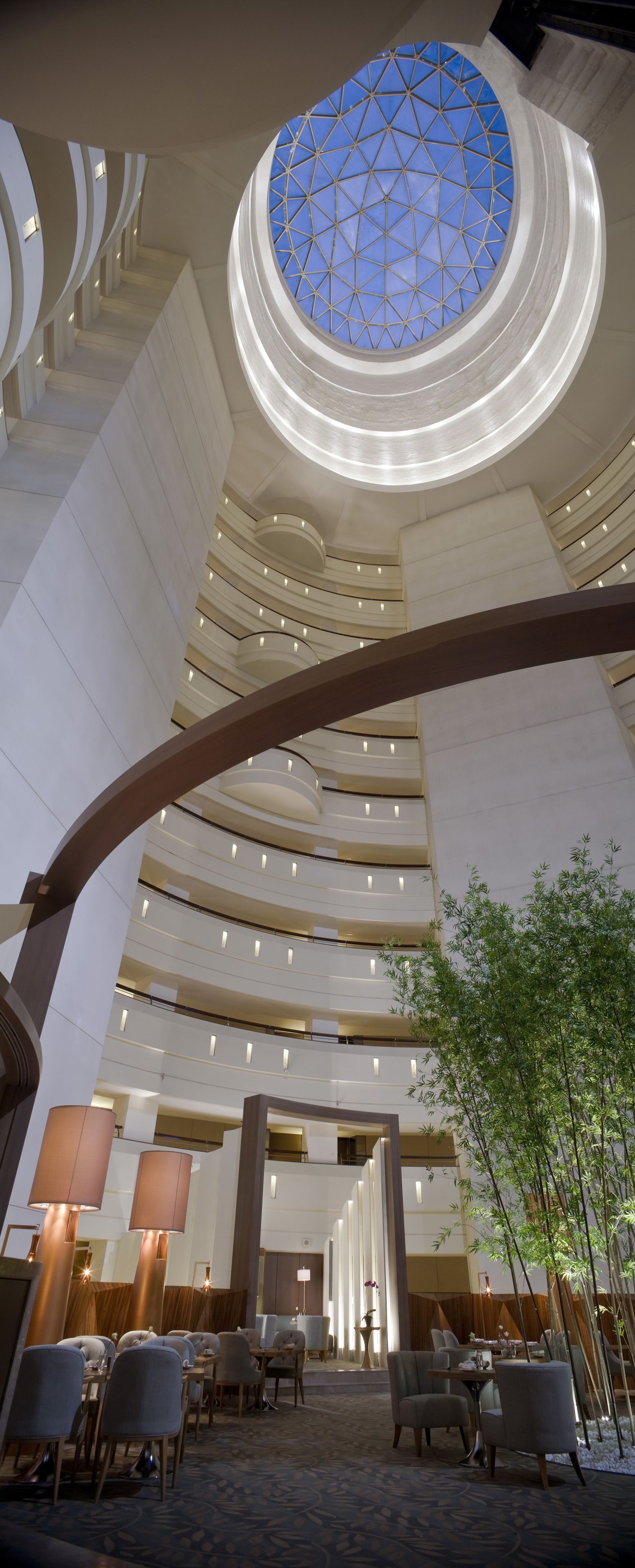 A modern hotel interior with a central atrium, multiple floors, and a large skylight.