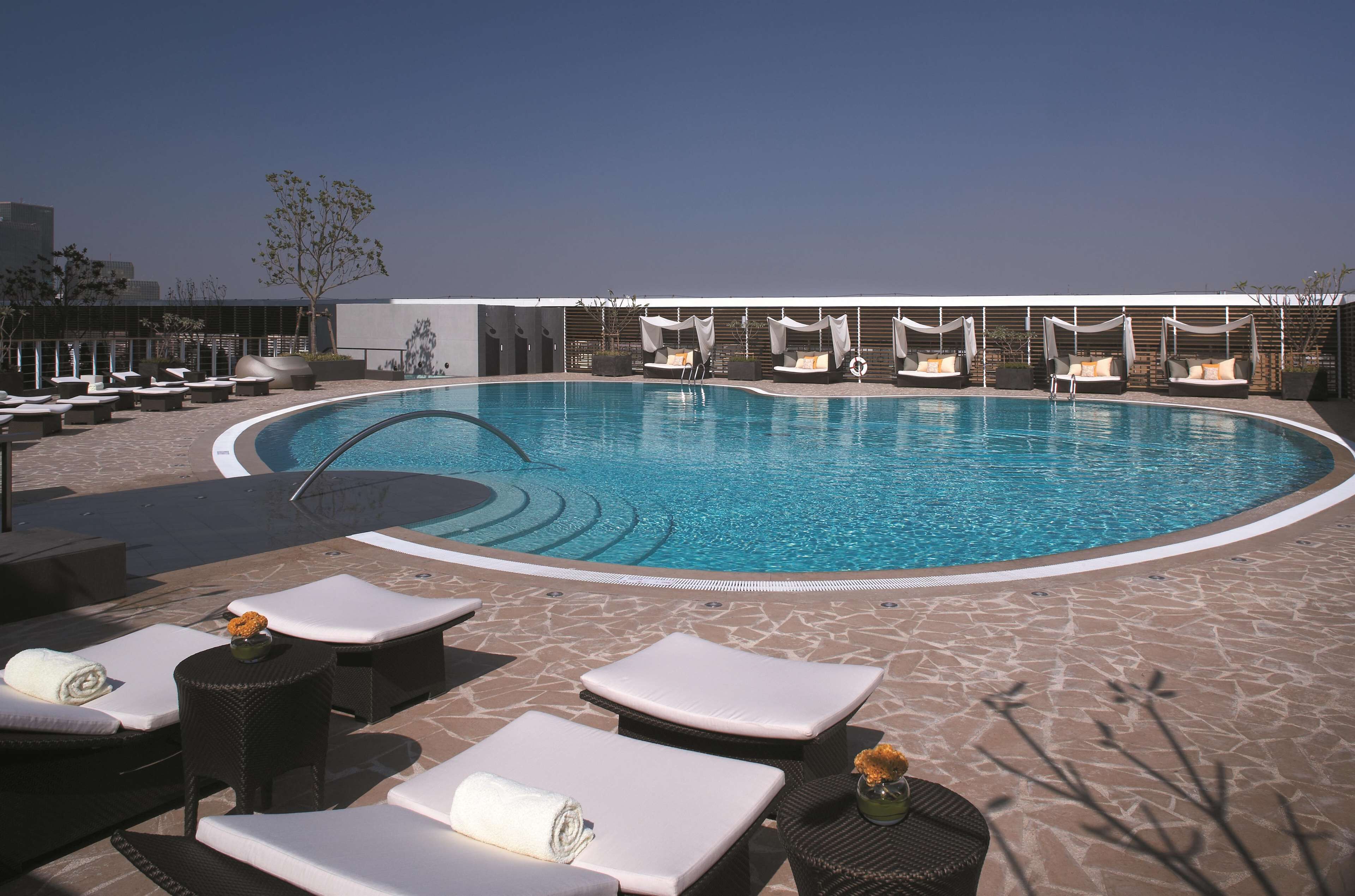 A pool area with lounge chairs, a small table with a vase, and a clear blue pool.