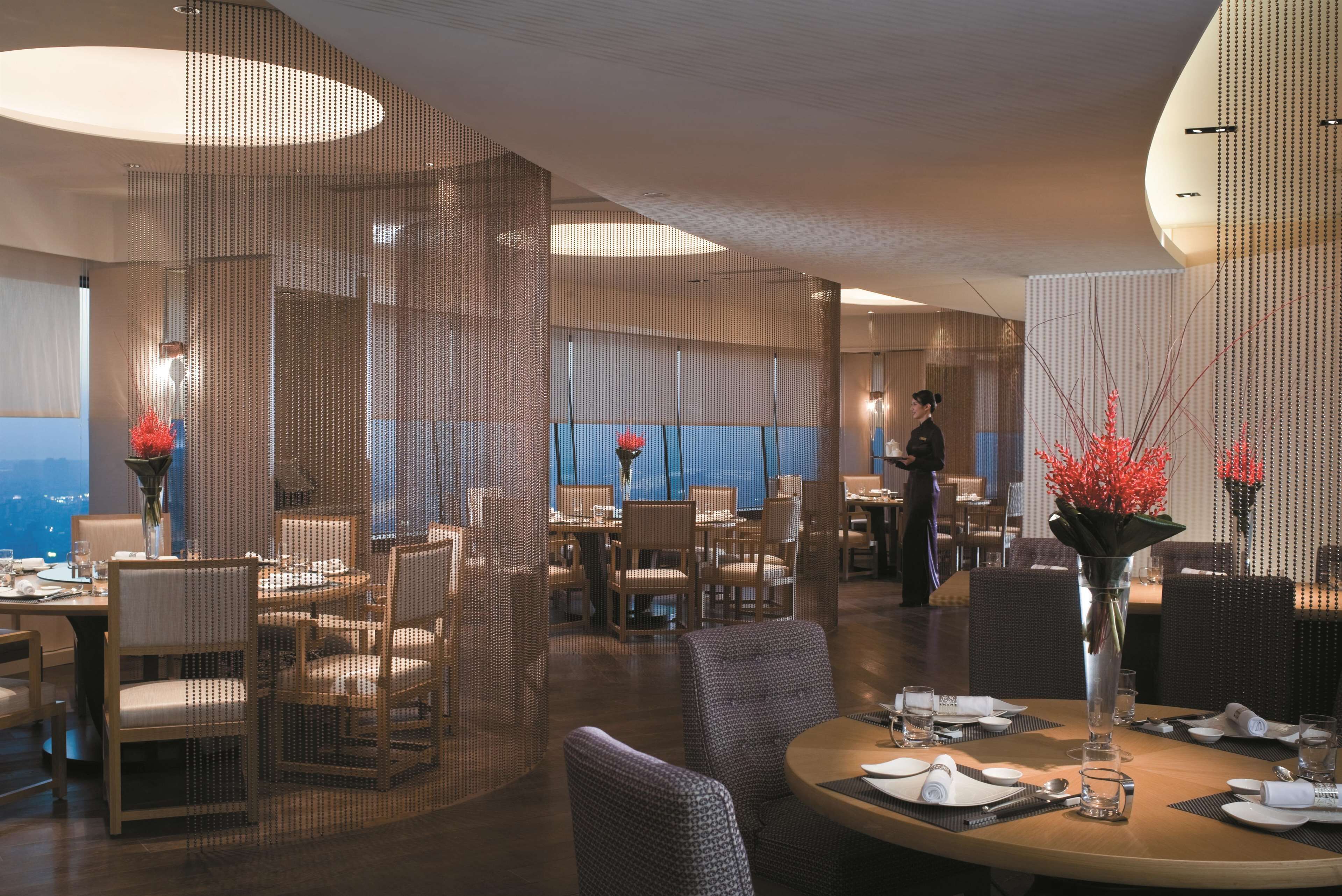 Un comedor moderno con techos altos, ventanas amplias y vistas a la ciudad.