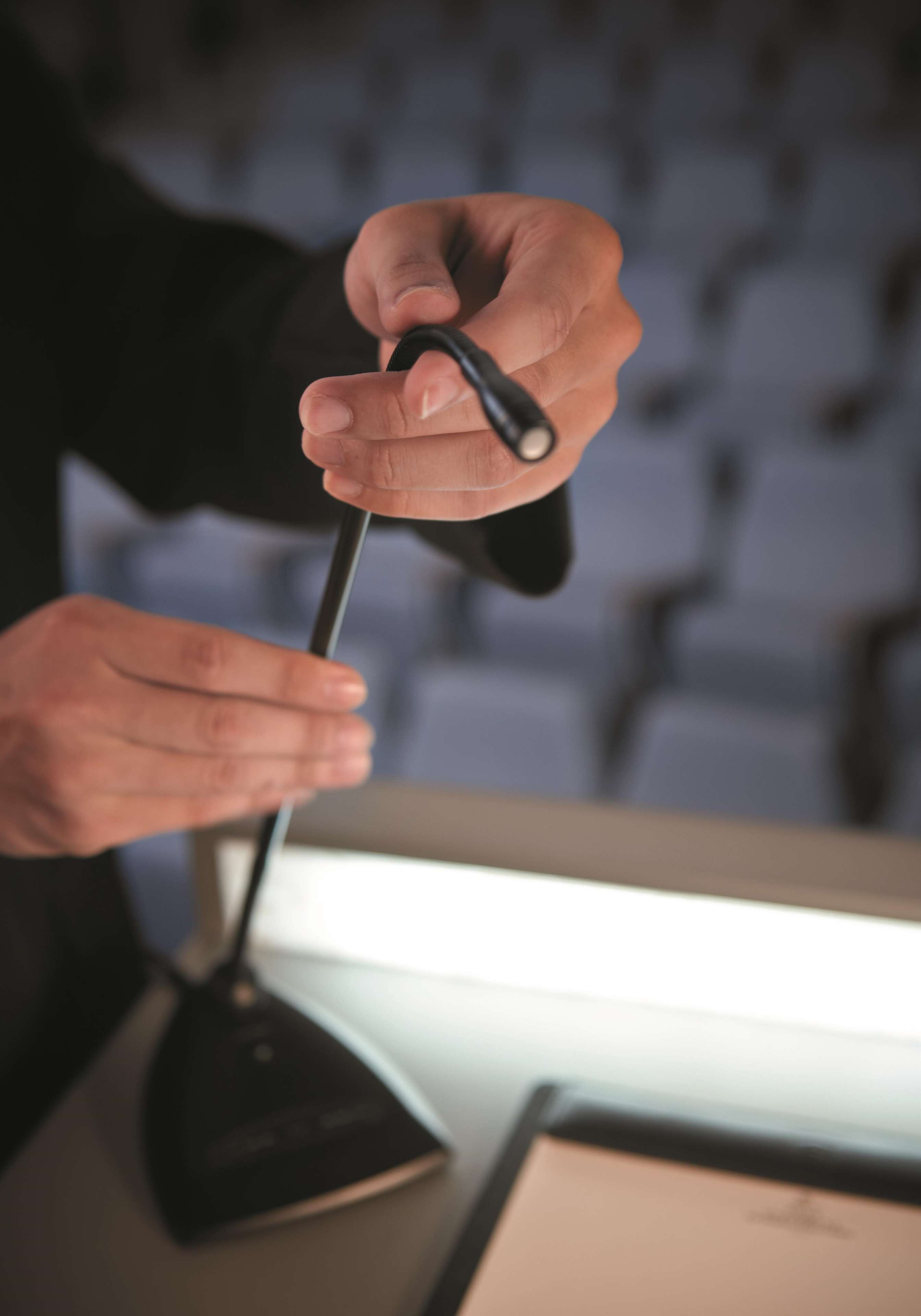 A person holding a black object, possibly a remote control, with a blurred background.
