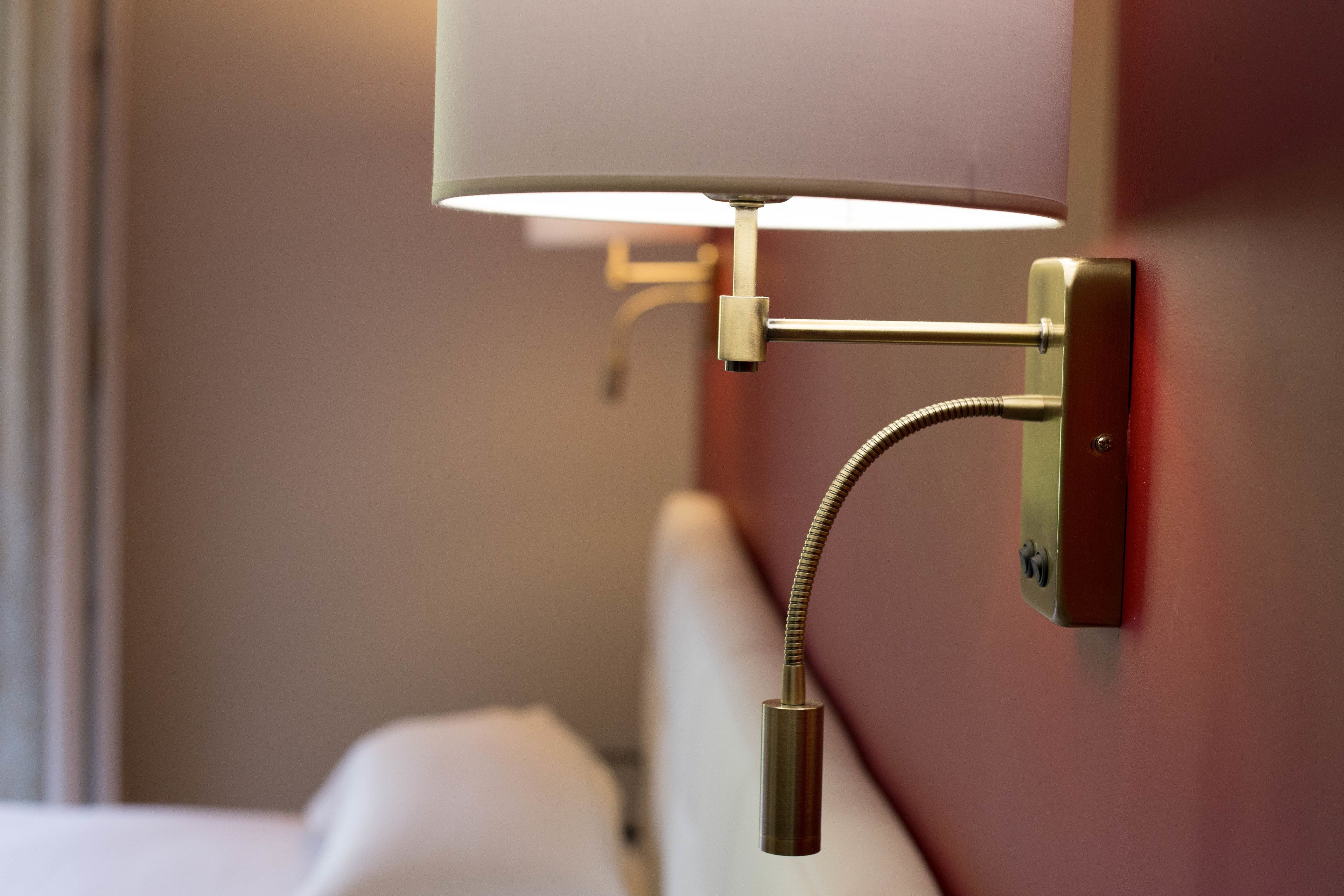 A wall-mounted lamp with a flexible neck and a pull chain.