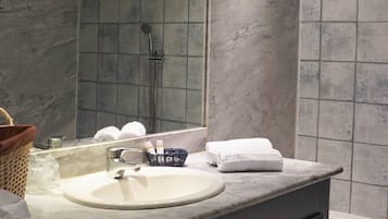 A modern bathroom with a marble sink, a large mirror, and a shower area.