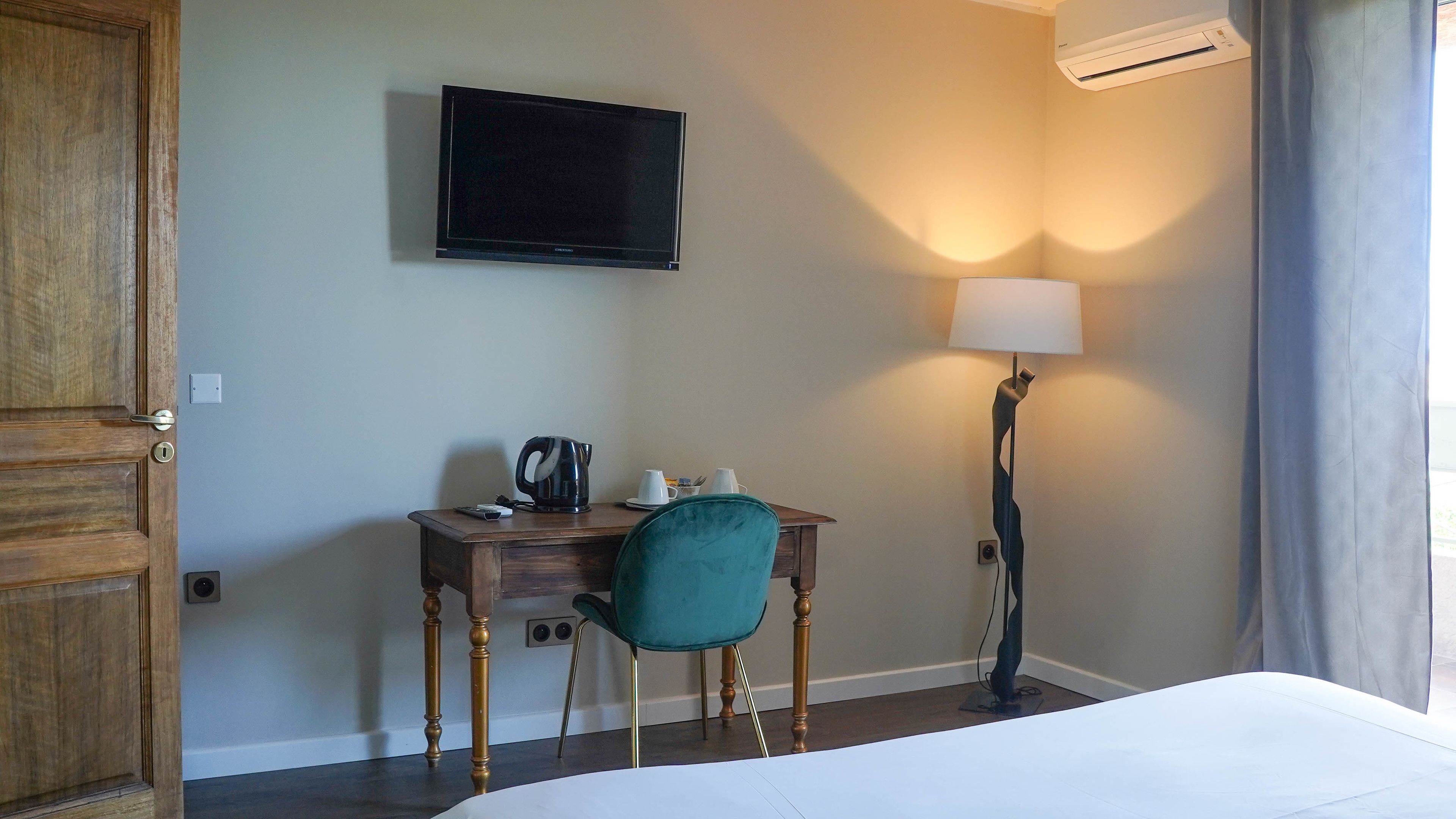 Une chambre d’hôtel équipée d’un lit, d’un bureau avec une chaise, d’une télévision, d’une lampe et d’un appareil de climatisation.
