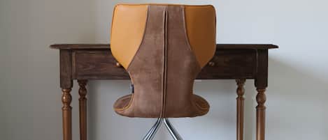 A chair with a high back and metal legs, positioned in front of a wooden table.