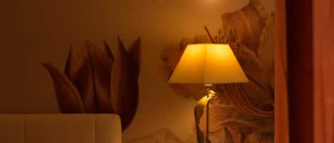 Une chambre d’hôtel avec un lit, une table de chevet avec une lampe et une fresque florale sur le mur.