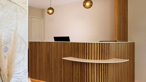 A reception desk with a wooden finish, two pendant lights, and a marble floor.