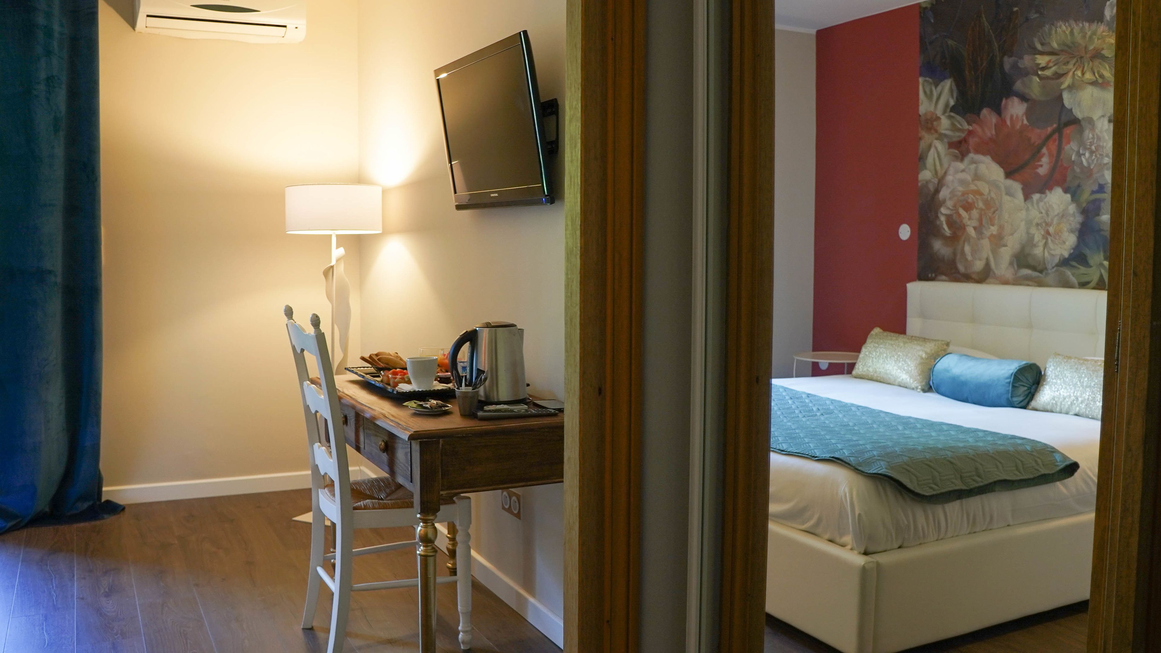 Une chambre d’hôtel avec un lit, un bureau doté d’une lampe, une télévision et un tableau accroché au mur.