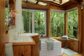 A wooden bathroom with a large window, a sink, and a bathtub.