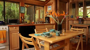 A wooden kitchen with a dining table, chairs, and a coffee maker. - Volcano Rainforest Retreat (Volcano)