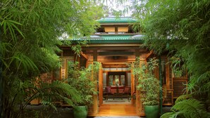 A traditional Japanese-style building with a wooden entrance, surrounded by lush bamboo and ferns. - Volcano Rainforest Retreat (Volcano)