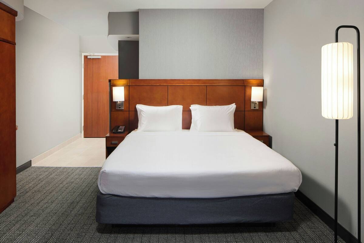 Ein Hotelzimmer mit einem großen Bett, einem Holzkopfteil, zwei Nachttischlampen und einem Nachttisch.