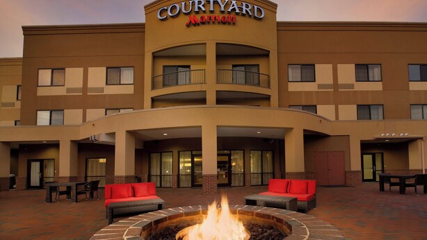 Un hotel Courtyard Marriott con un brasero en el patio, asientos al aire libre y fachada de ladrillo.