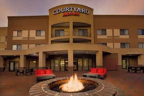 Un hotel Courtyard Marriott con un brasero en el patio, asientos al aire libre y fachada de ladrillo.