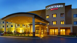 Entrada de un hotel Courtyard Marriott con un paseo techado, varias ventanas y una fachada bien iluminada.