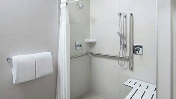 A modern shower area with a grab bar, a towel rack, and a showerhead.